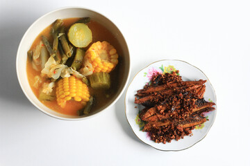 Sayur asem or sayur asam (Indonesian vegetable in tamarind soup) and Tongkol goreng bawang or fried tuna mackerel, isolated on white background. 