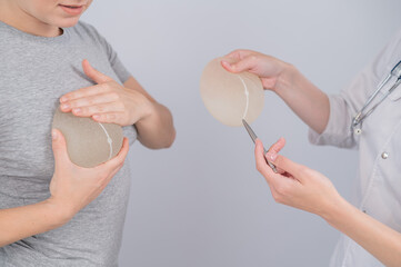 Caucasian woman trying on breast implants. A plastic surgeon helps a patient with a choice.