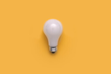 Overhead flat lay of a single white light bulb against a yellow background
