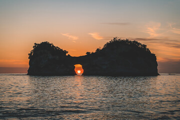 大きな岩の穴の中に落ちる夕日