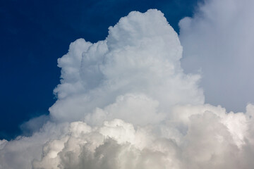 Big White fluffy cumulonimbus storm clouds in deep blue sky