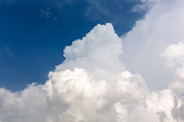 Big White fluffy cumulonimbus storm clouds in deep blue sky