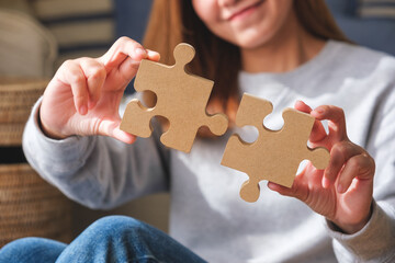 Closeup image of a woman holding and putting a piece of wooden jigsaw puzzle together - Powered by Adobe