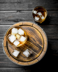 Whiskey in glasses with ice on the barrel.