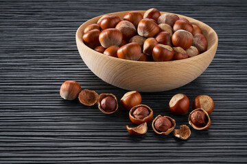 hazelnut in wooden bowl on black table.