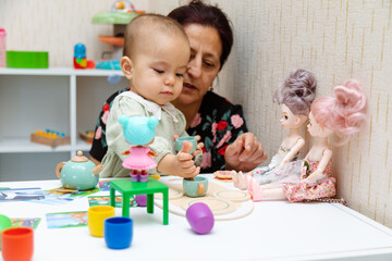 Obraz na płótnie Canvas Grandmother and toddler playing with toys at home