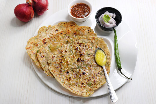 Indian traditional Hot Onion Paratha with tomato chutney. Indian onion stuffed Flatbread. also known as Pyaz ke parathe in Hindi. over a light background with copy space.