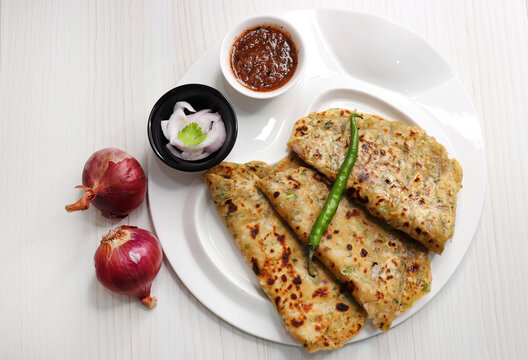 Indian traditional Hot Onion Paratha with tomato chutney. Indian onion stuffed Flatbread. also known as Pyaz ke parathe in Hindi. over a light background with copy space.