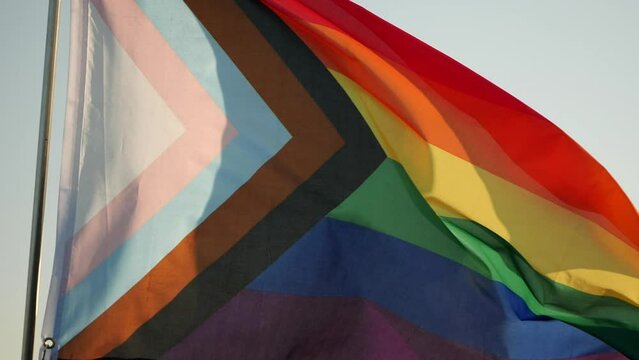 LGBT Pride Flag Waving. Rainbow LGBT, pride, flag is symbol Gay, Lesbian, Peace, Pride, LGBTQ, Bisexual, Homosexual, Transgender, Love. Rainbow flag waving on sunset, soft focus. Slow motion