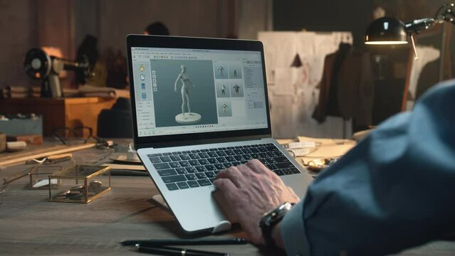 Fashion designer creates clothes and develops future wear collection in 3D modeling program. Male tailor works in luxury designer workshop or tailoring studio on laptop. Fashion concept.
