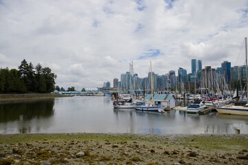 Fototapeta na wymiar Summer trip across America - Stanley Park waterfront, downtown Vancouver, harbor with yachts and boats, skyscrapers and nature. Calm water of the bay, low tide.