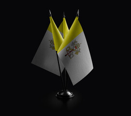 Small national flags of the Vatican on a black background