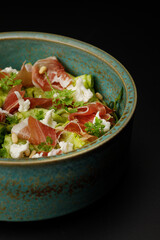 Pasta with prosciutto and fried zucchini over black background