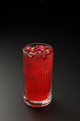 Glass of iced cocktail served with flowers on top, dark background
