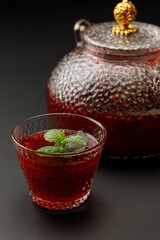 Fresh fruit tea in glass cup with teapot on background