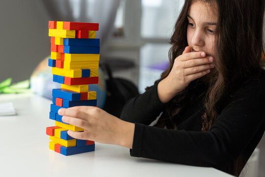 Children building wood blocks at playground. Girl kid playing stacking wood blocks (Jenga games) for meditation practice. Hand movement control Building Computational Skills Children's play concept.