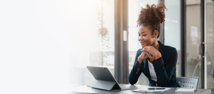 Young African American female working with tablet computer on remote project watching webinar. doing corporate data digital technology analysis.