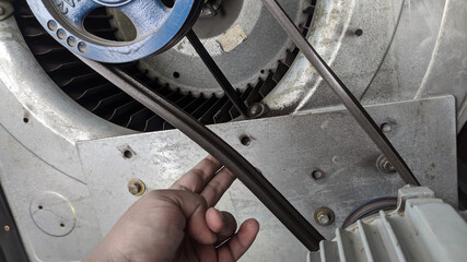 Checking the tenssion of the V belt pulley using hand estimates.