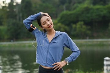 Beautiful woman stretching arms and breathing fresh air while exercising in the park. Sport and healthy lifestyle concept