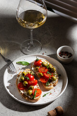 Bruschetta with fresh tomatoes and olives on a plate and wineglass