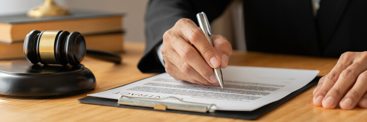 Asian female legal advisor or a lawyer using a pen to check business information and various...