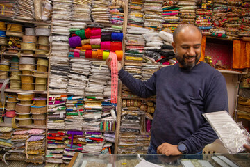 Male fabric vendor showing border and lace to a buyer