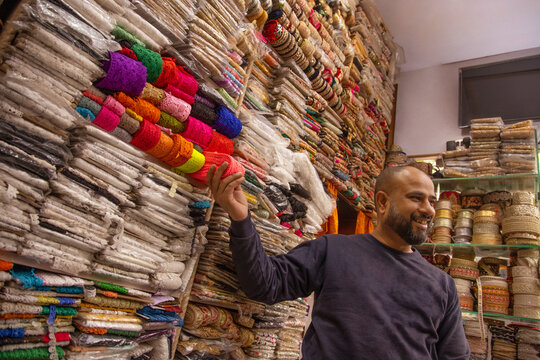 Male fabric vendor showing border and lace to a buyer