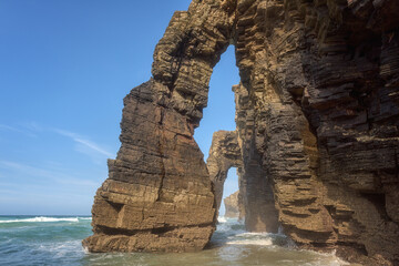 Natural stone arches of Cathedrals beach (Playa de las Catedrales) or Praia de Augas Santas, amazing landscape with rocks in the ocean and blue sky, Ribadeo, Galicia, Spain. Outdoor travel background