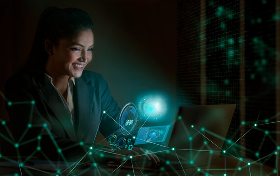 Businesswoman working on laptop computer with icons on virtual screen