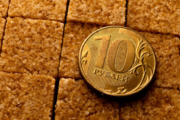 The value of currency and the value of sweetness, both represented by the golden coin and brown sugar in the image - 561203515