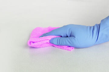 a hand in a blue glove wipes the surface with pink microfiber. High quality photo