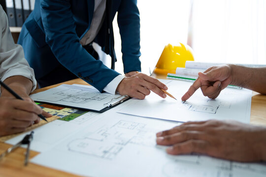Businessman and architect meeting for planing and checking house design and house model and secretary takes notes, the architect design working drawing sketch plans blueprints