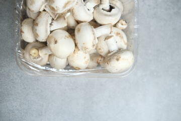 Champignon mushrooms in the plastic box at the grey background	