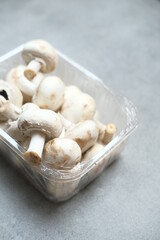 Champignon mushrooms in the plastic box at the grey background	