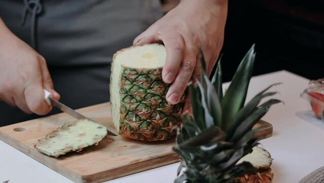 carving a pineapple on a board with a fruit salad knife