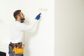 Painter Painting a House Wall with a Paint Roller.
