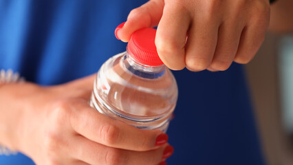 Woman opens plastic bottle with water closeup