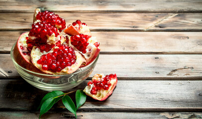 Pieces of ripe pomegranate in glass bowl with leaves.