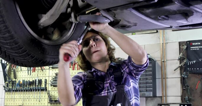 Beautiful Woman Car Mechanic Works In A Car Service - The Camera Is Moving From Left To Right