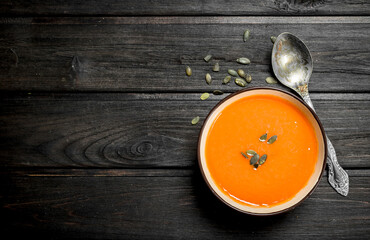 Pumpkin soup in bowl with spoon.