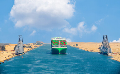 Large container ship, accompanied by tugboat, passing through the Suez Canal in Egypt.  Railway...