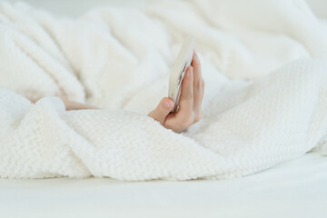 Fototapeta na wymiar hand holding phone in bed