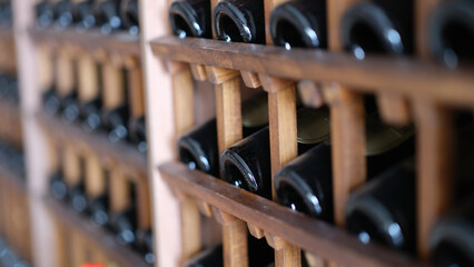 Resting dusty wine bottles stacked on wooden racks in basement