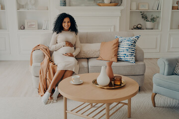Charming with hands on her belly, being in third trimester
