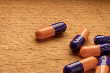 A photograph of blue and orange pills on a wooden table, representing the natural and organic treatment options available - 561213574