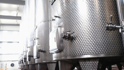 Modern automated winery with lines of metal tanks. Interior view of modern brewery with stainless steel barrels