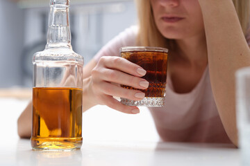 Drunk woman holding glass of whiskey and alcoholics alone