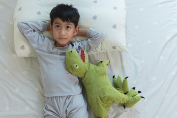 Top View of Asian boy smiling lying down on Bed in bedroom at home