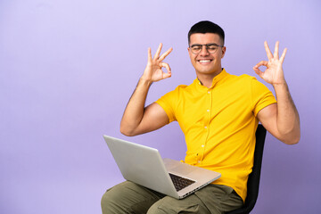 Young man sitting on a chair with laptop in zen pose
