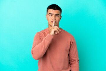 Young handsome man over isolated blue background showing a sign of silence gesture putting finger in mouth